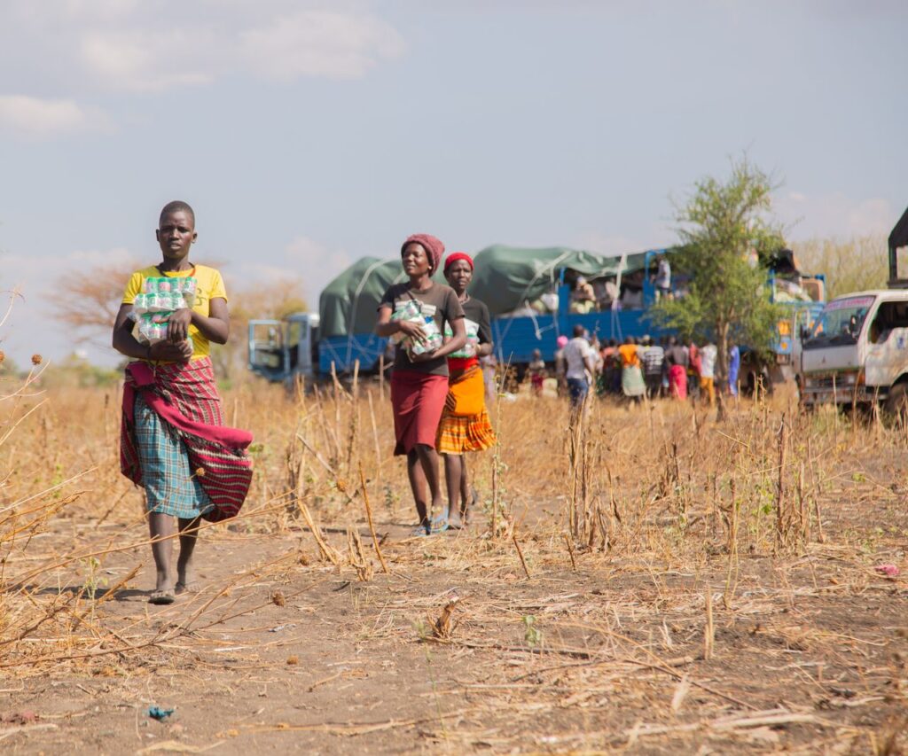People receiving humanitarian aid in a rural area during daytime.